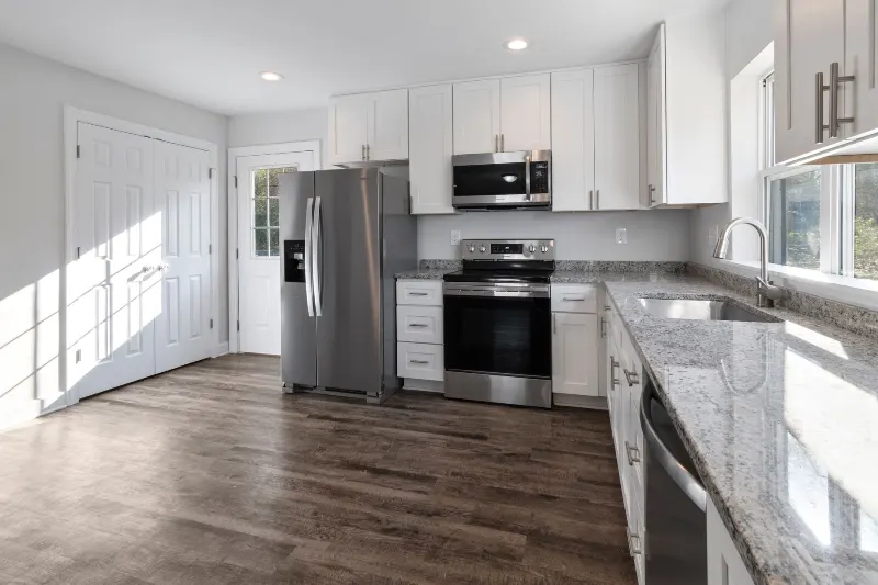Finished kitchen with white cabinets and wood flooring