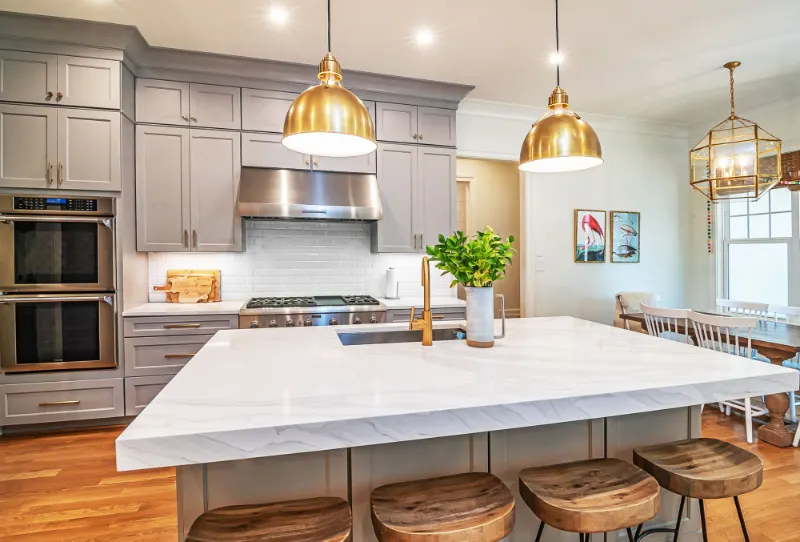 Kitchen with marble island, grey cabinets and brass pendant lights